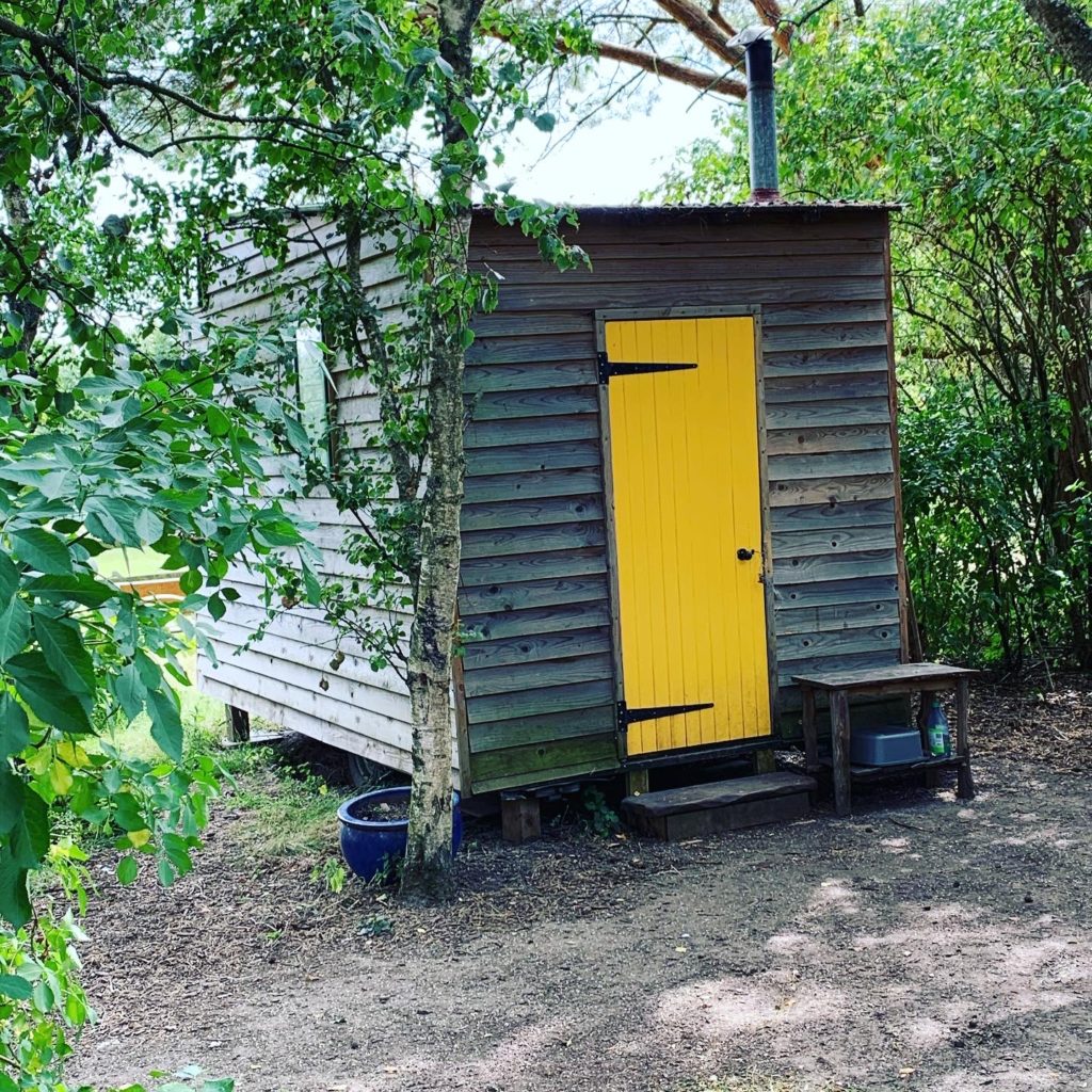 Small hut in woods with yellow door